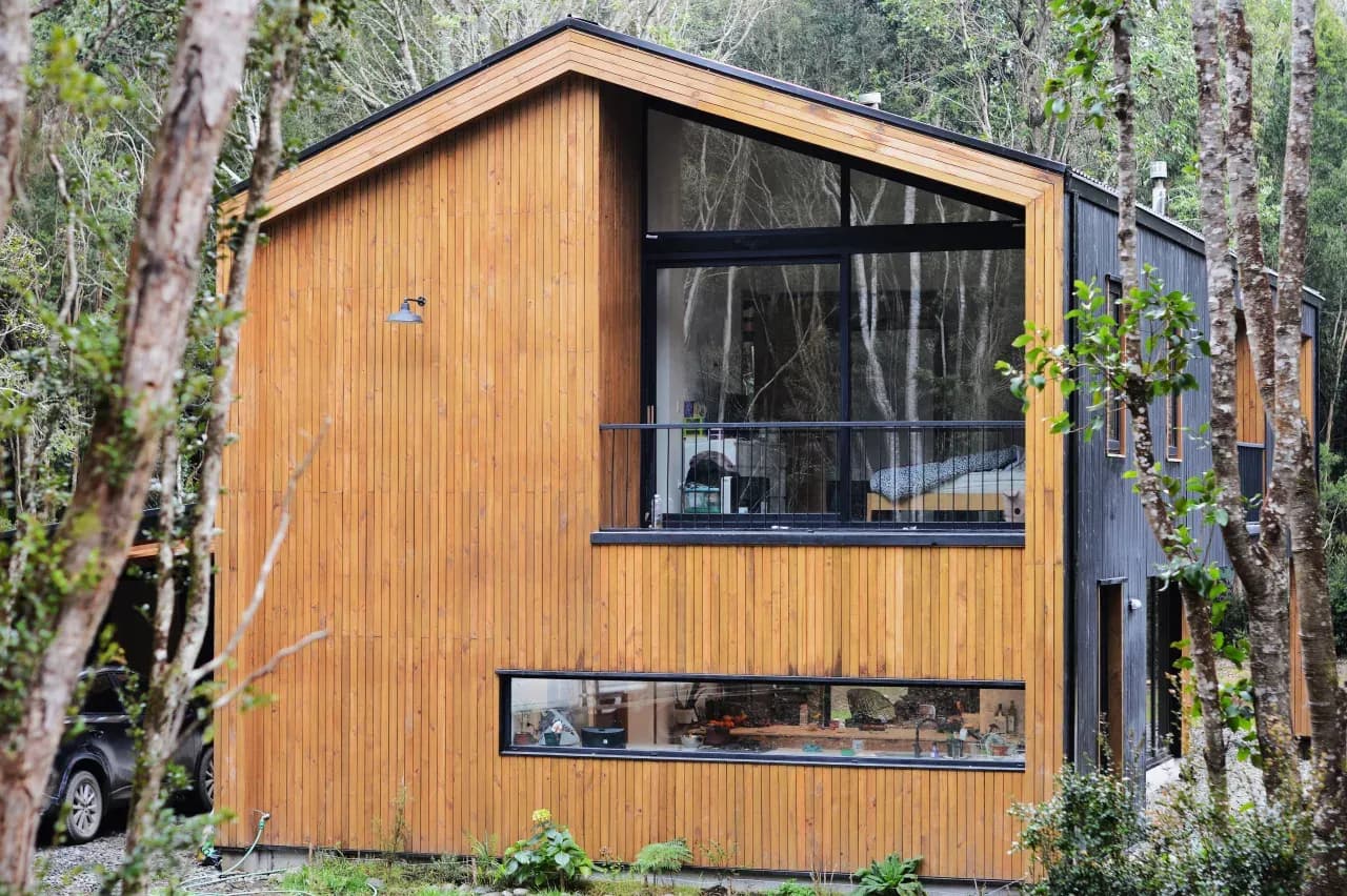 Casa con ventanas de PVC negro en termopanel y revestimiento de madera, obra de DM Cristales