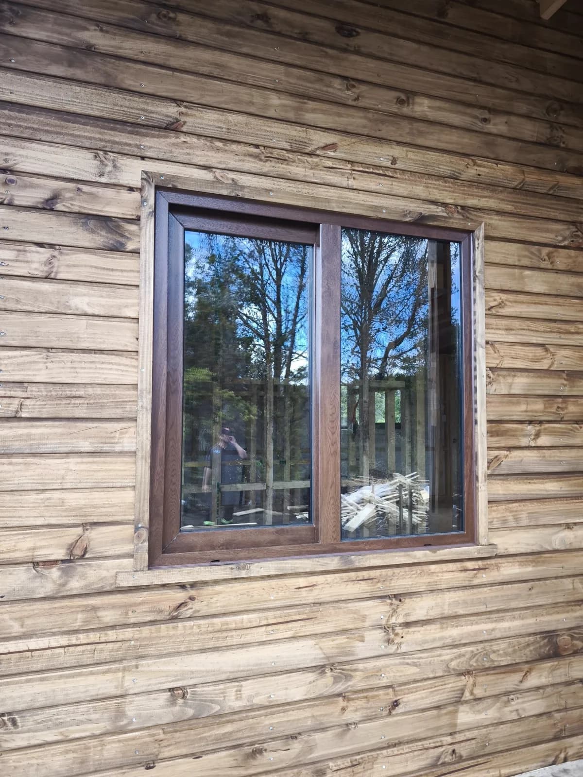 Ventana europea de PVC negro con termopanel sobre revestimiento de madera, obra de DM Cristales